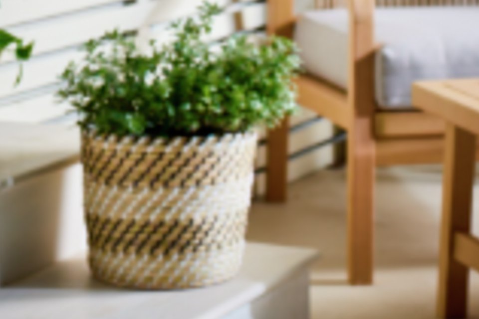 A Habitat faux seagrass planter with plants on a patio.